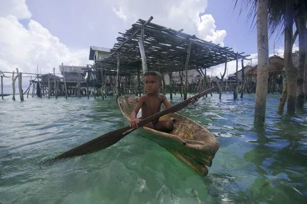 SEMPORNA, MALASIA - 3 DE JULIO: Un niño gitano del mar local remando en un barco Fotos De Stock Sin Royalties Gratis